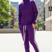 Person wearing a purple tracksuit with white stripes  taken outside