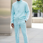 Person wearing a light blue tracksuit with white stripes taken outside