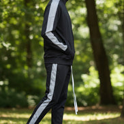 Person wearing a black tracksuit with white stripes taken outside