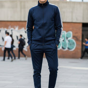 Man wearing a navy tracksuit with white stripes  taken  outside