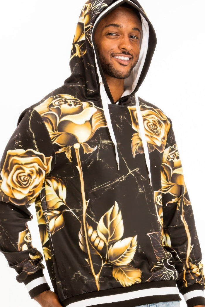 Man wearing a black hoodie with gold rose designs on a white background