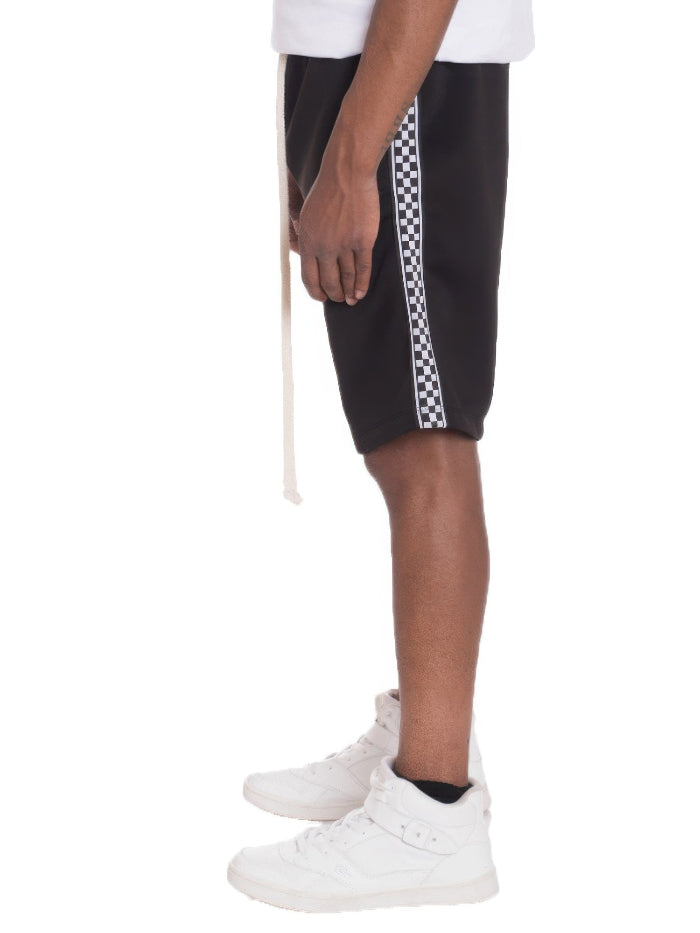 Black shorts with white checkered stripes worn by a person on a white background