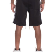 Black shorts with white and red striped side panels worn by a person on a white background