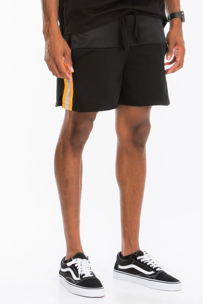 Person wearing black shorts with a white and orange stripe on a white background