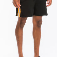 Person wearing black shorts with a white and orange stripe on a white background