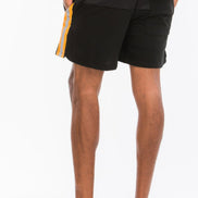 Person wearing black shorts with a yellow stripe on a white background
