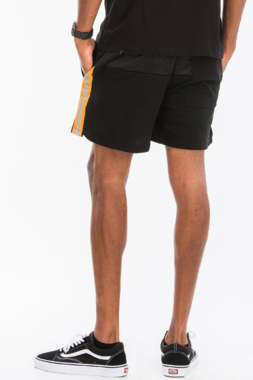 Person wearing black shorts with a yellow stripe on a white background