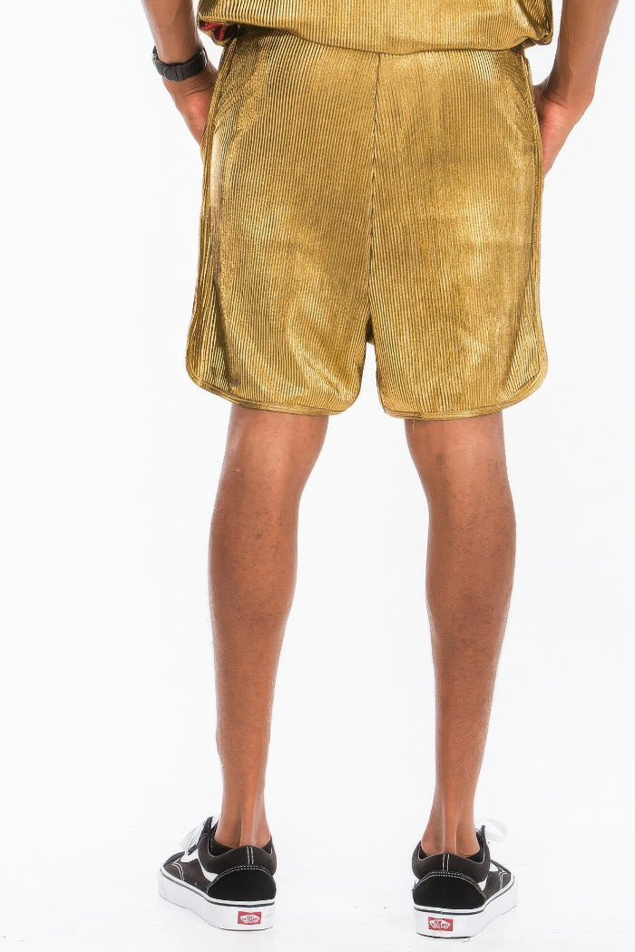Gold corduroy shorts worn by a person on a white background