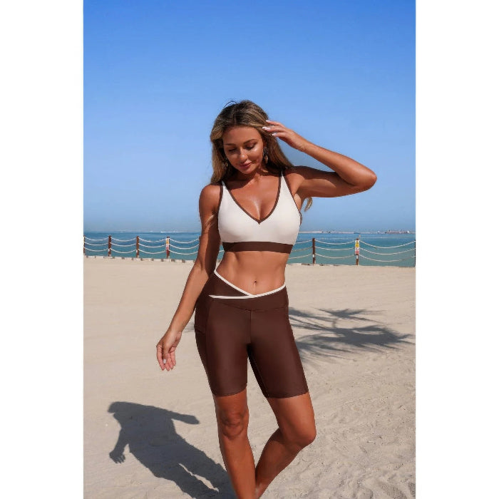 Woman in a black and white sports bra and shorts on a beach.