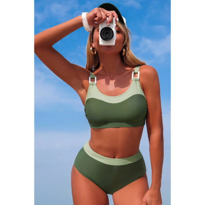Woman in a green bikini taking a selfie against a blue sky.