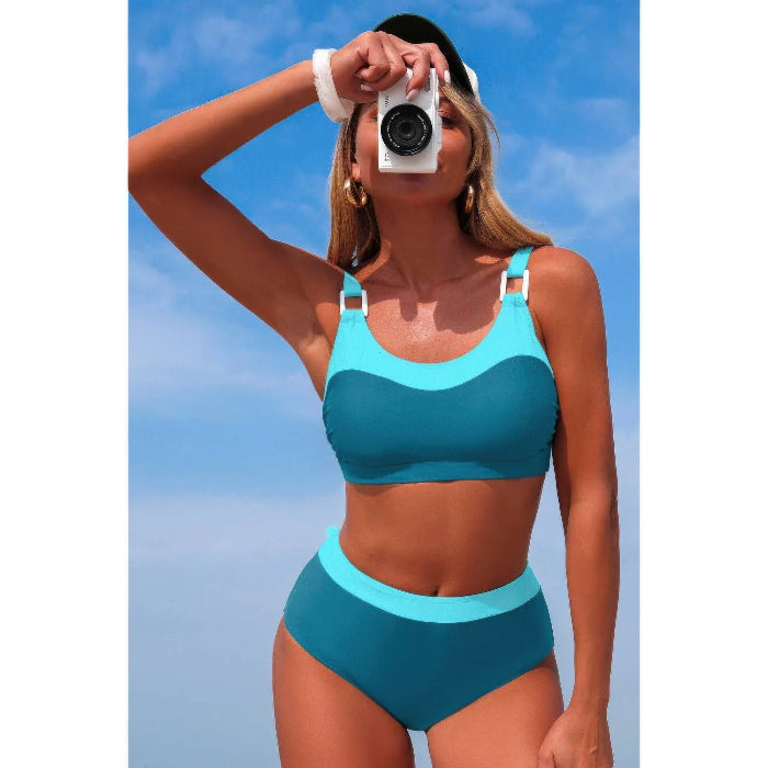 Woman in a blue bikini taking a selfie against a clear blue sky.