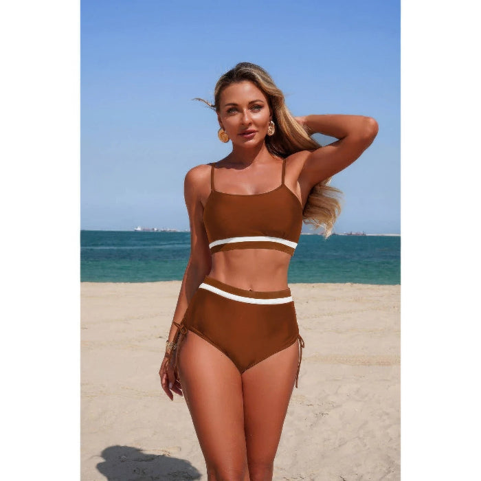 Woman in a brown bikini with white accents standing on a beach.