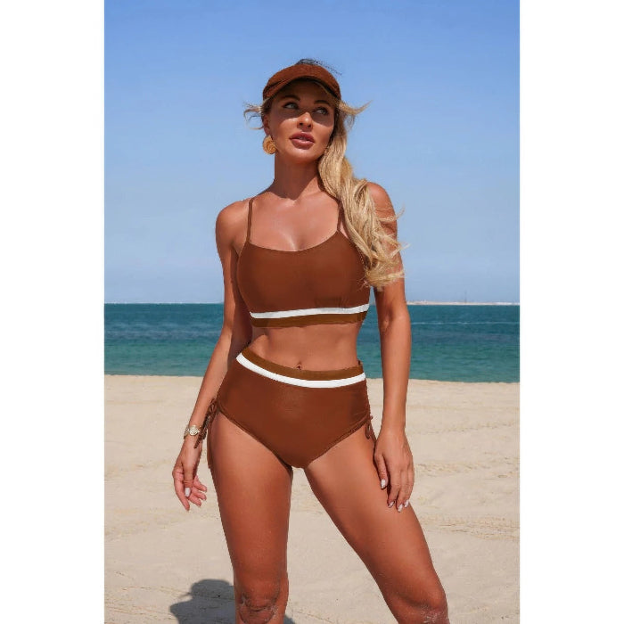 Woman in a brown bikini with white accents standing on a beach.