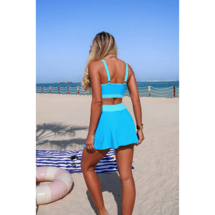 Woman in a blue swimsuit standing on a beach with ocean view