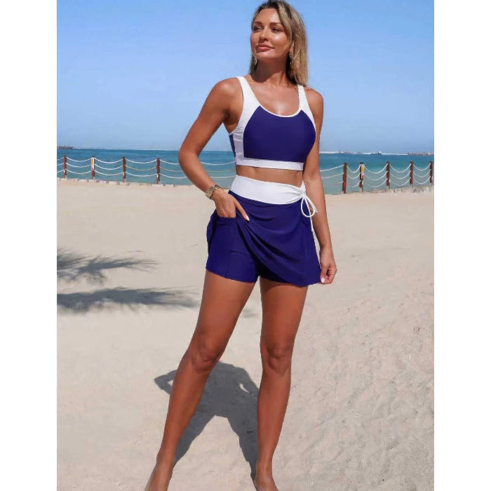 Woman in a blue and white sports outfit standing on a beach.
