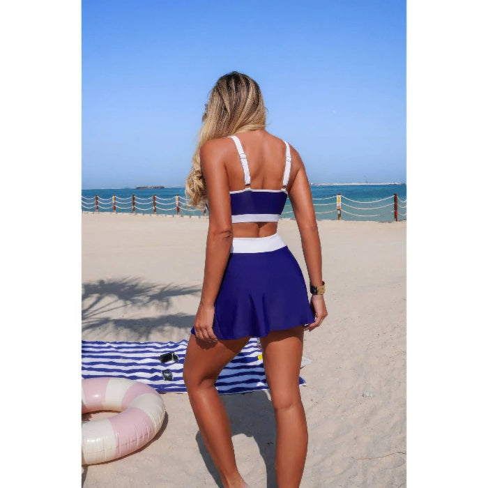 Woman in a blue and white swimsuit standing on a beach with ocean view
