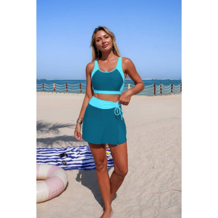 Woman in teal sports outfit standing on a beach with ocean view