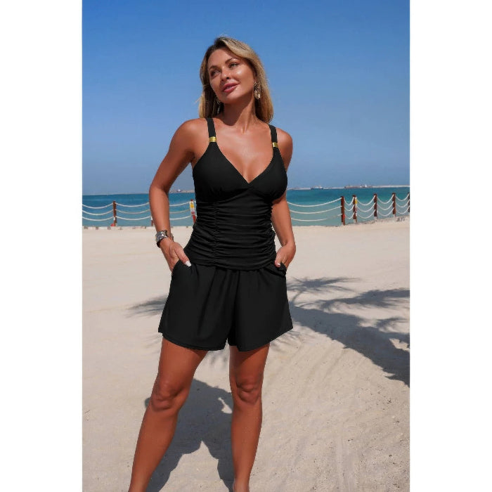 Woman in a black swimsuit standing on a beach with ocean view