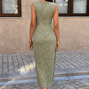 A woman wearing a sleeveless, knee-length sage green lace dress, photographed from behind in an outdoor setting 