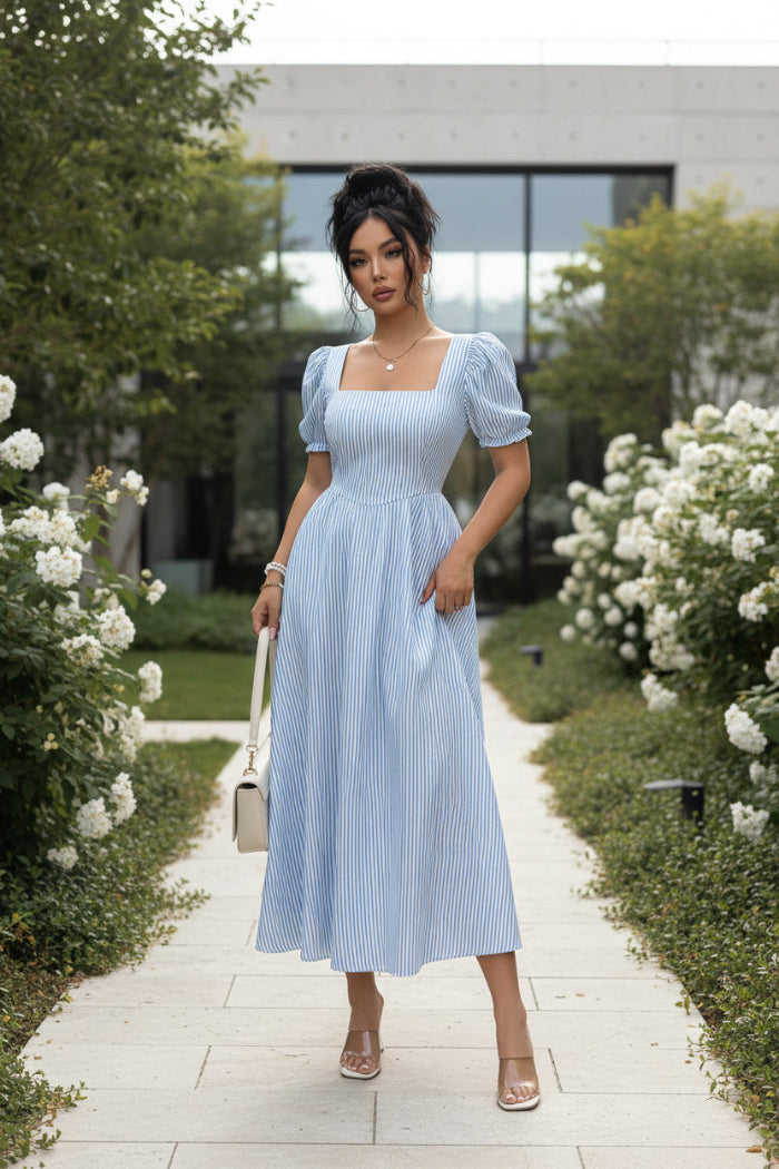 Woman wearing a light blue striped dress with a plain background