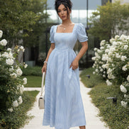 Woman wearing a light blue striped dress with a plain background