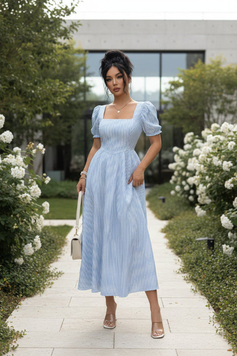 Woman wearing a light blue striped dress with a plain background