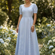 Woman wearing a blue and white striped dress in a minimal indoor setting