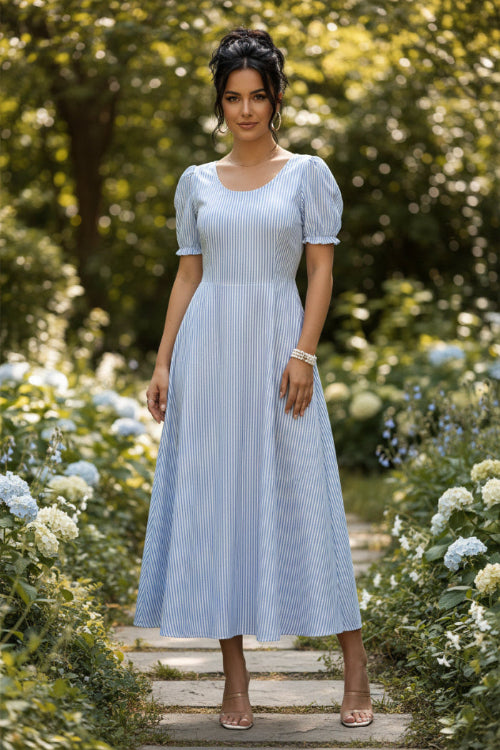 Woman wearing a blue and white striped dress in a minimal indoor setting