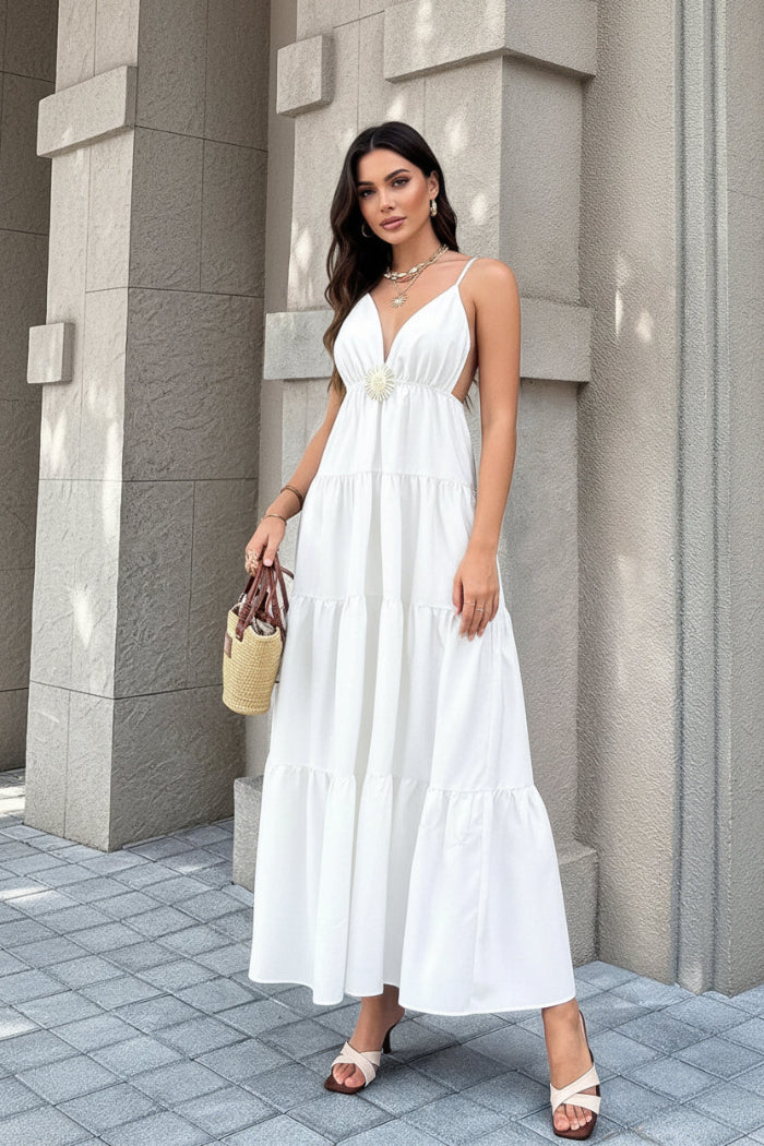 Woman wearing a white dress standing against a gray stone wall.