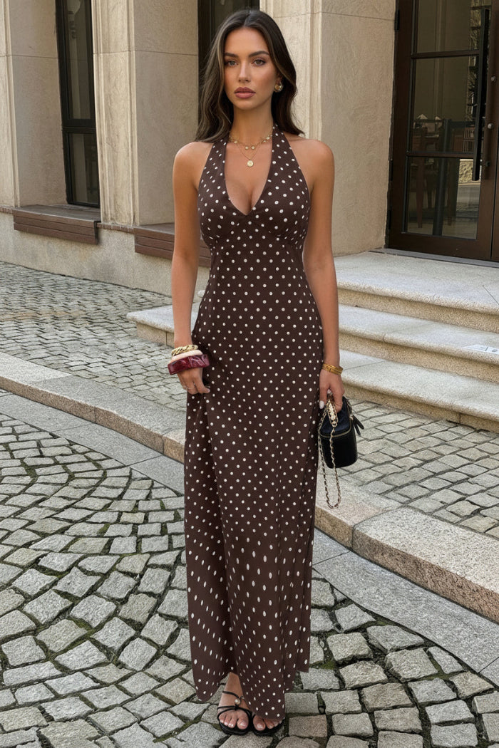 Woman wearing a brown polka dot dress on a cobblestone street.