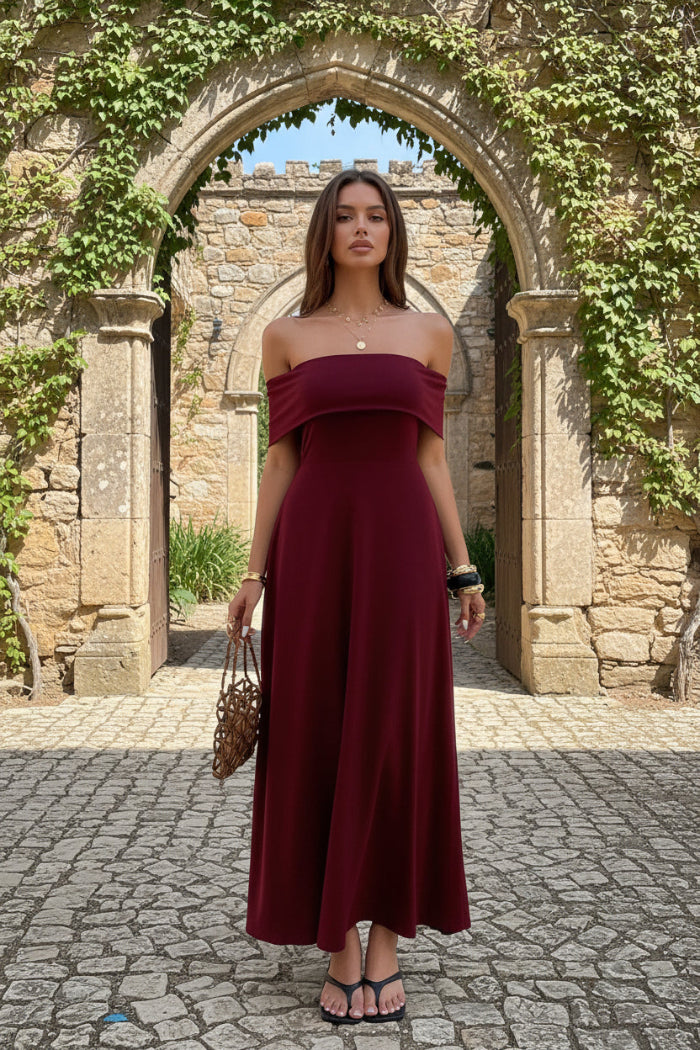Woman wearing a burgundy off-shoulder dress standing outdoors.