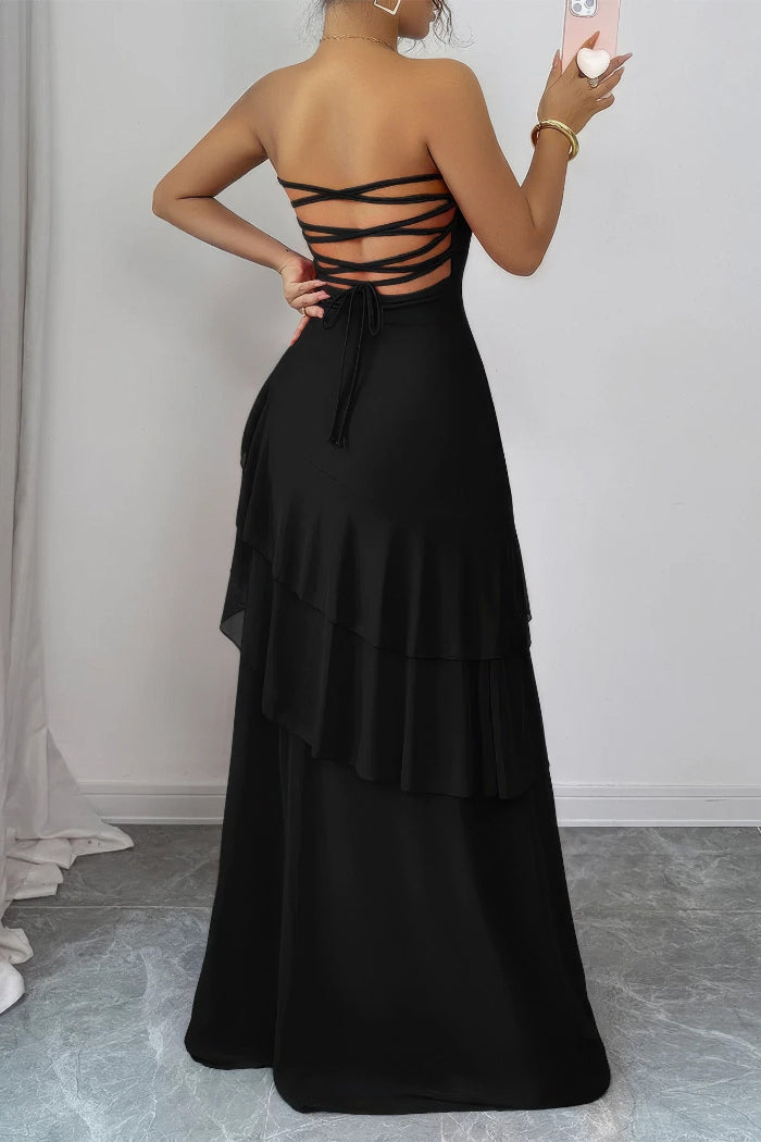A woman wearing a black strapless maxi dress with a strappy lace-up back, shown from behind in a mirror selfie.