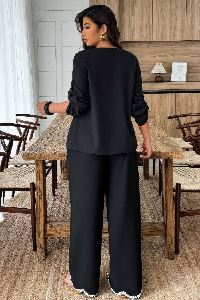 Woman in a black outfit standing in a dining area with wooden tables and chairs.