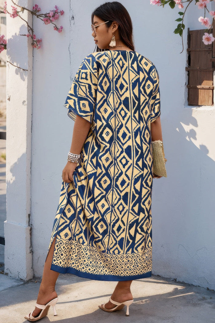 A woman wearing a navy blue and beige geometric print kurta dress, standing outdoors against a white wall with pink flowers.