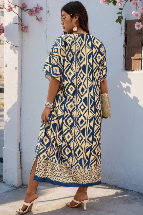 A woman wearing a navy blue and beige geometric print kurta dress, standing outdoors against a white wall with pink flowers.
