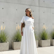 Woman wearing a white off-shoulder dress standing outdoors.