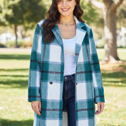 Woman wearing a plaid coat outdoors with trees and a building in the background