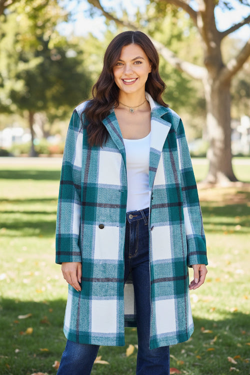 Woman wearing a plaid coat outdoors with trees and a building in the background
