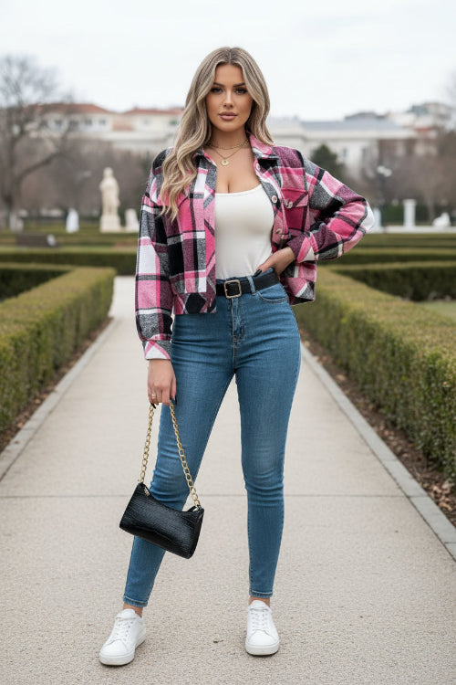 Person wearing a pink and black plaid shirt with blue jeans indoors.