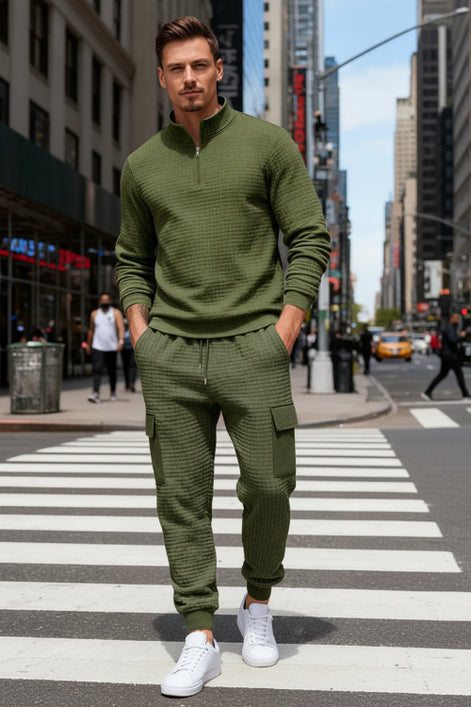 A man wearing an olive green textured quarter-zip pullover and matching cargo jogger pants 