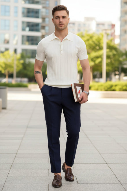 Man wearing a white short-sleeve shirt and dark pants, holding a book with a wooden cover.