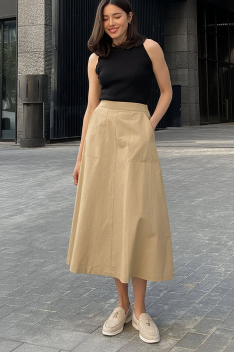 Woman wearing a black sleeveless top and beige skirt on a stone pavement.