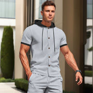 A man wearing a light gray two-piece tracksuit with a short-sleeve button-front hoodie top 