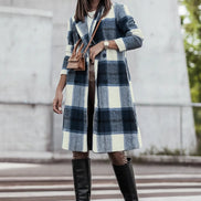 Woman wearing a plaid coat and brown boots on a city street.