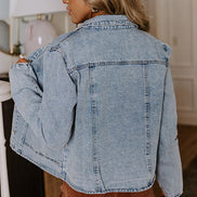 Person wearing a light blue denim jacket indoors