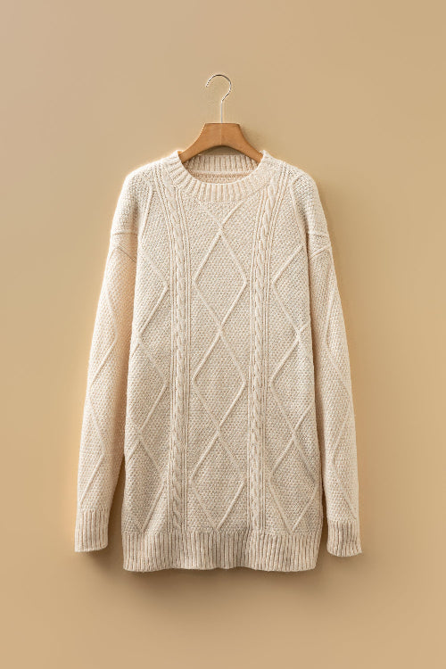 Beige cable knit sweater on a wooden hanger against a beige background