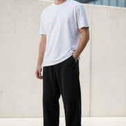 Black corduroy pants worn by a person on a white background