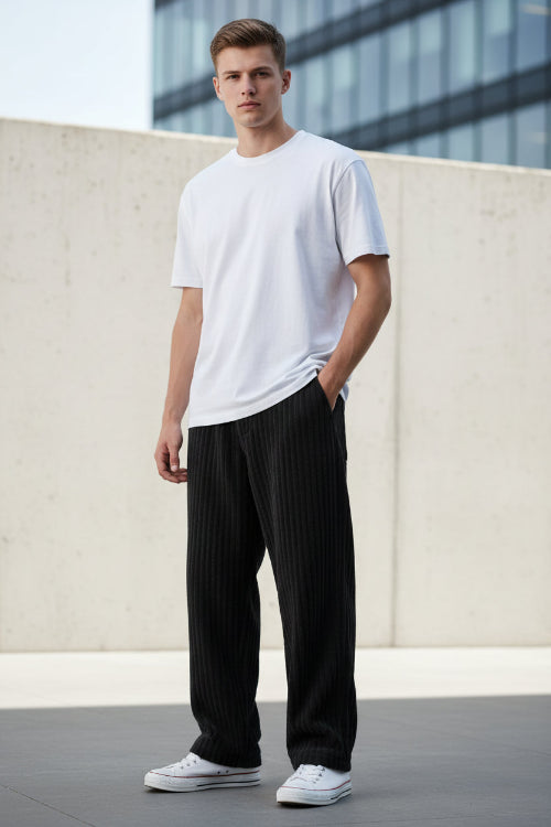 Black corduroy pants worn by a person on a white background
