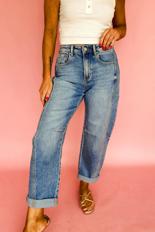 A person wearing light-wash blue straight-leg jeans with rolled cuffs, paired with a white ribbed tank top