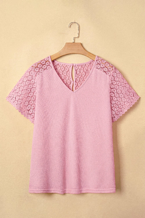 Pink checkered blouse with lace details on a hanger against a beige background